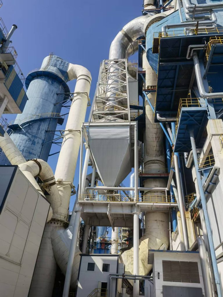 SCRcase-Jidong Heidelberg Jingyang Cement Co Ltd - Nanjing Sequoia Industrial Solutions Co.,ltd Industrial chemical plant with interwoven metal pipes blue towers and metal staircases against a clear blue sky
